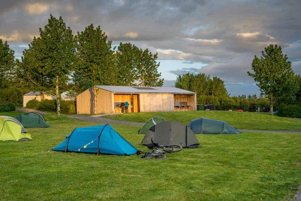 Tents and cottage on green field
