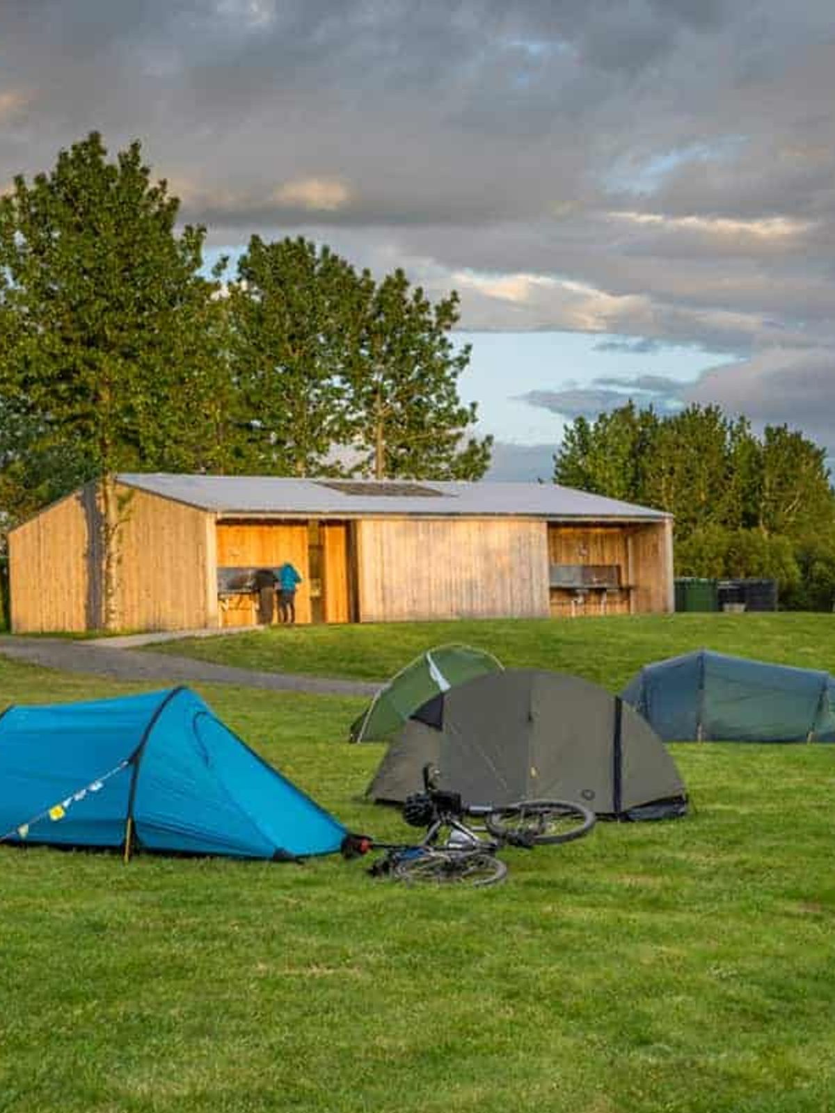 Tents and cottage on green field