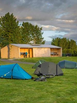 Tents and cottage on green field