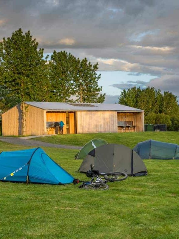 Tents and cottage on green field