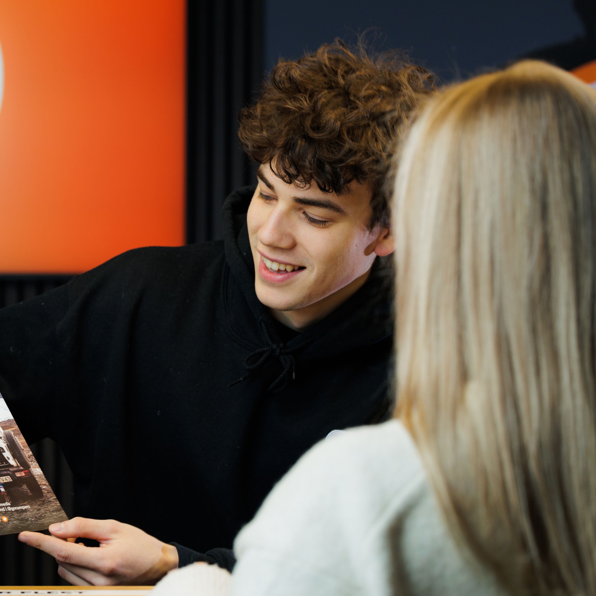 a man is giving a brochure to a woman at a counter .