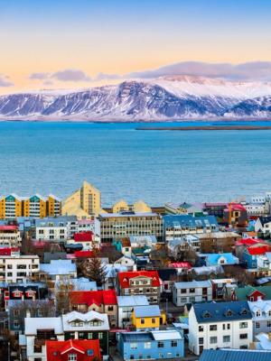 Aerial panorama of downtown Reykjavik at sunset with colorful houses and snowy mountains in the background