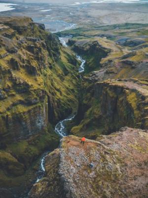 an aerial view of a person standing on a cliff overlooking a river .