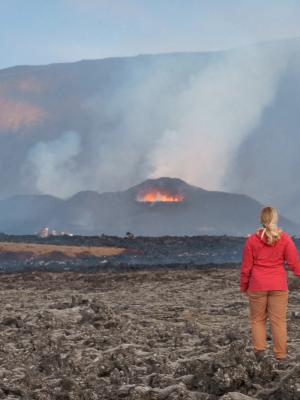 a man and a woman are holding hands while looking at a volcano .