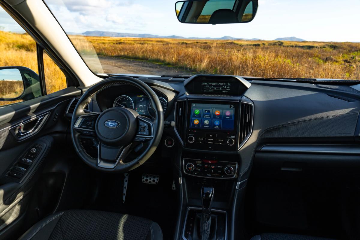 Subaru Forester driver view of the infotainment touchscreen and climate controls, with a gravel track ahead
