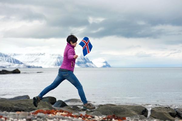 Tourist with an Icelandic flag jumping