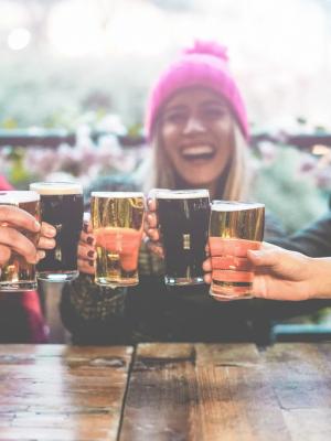 a group of people are sitting at a table toasting with beer glasses in a brewerie in Iceland.