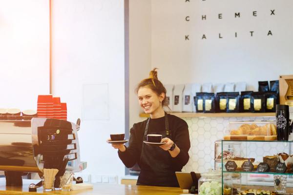 Coffee shop Friendly waitress holding a two cups of coffee at the local coffee shop