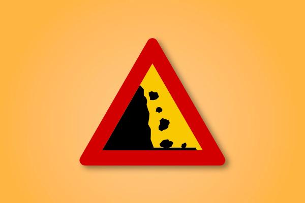 a red and yellow triangle road sign with a rock falling from a mountain .