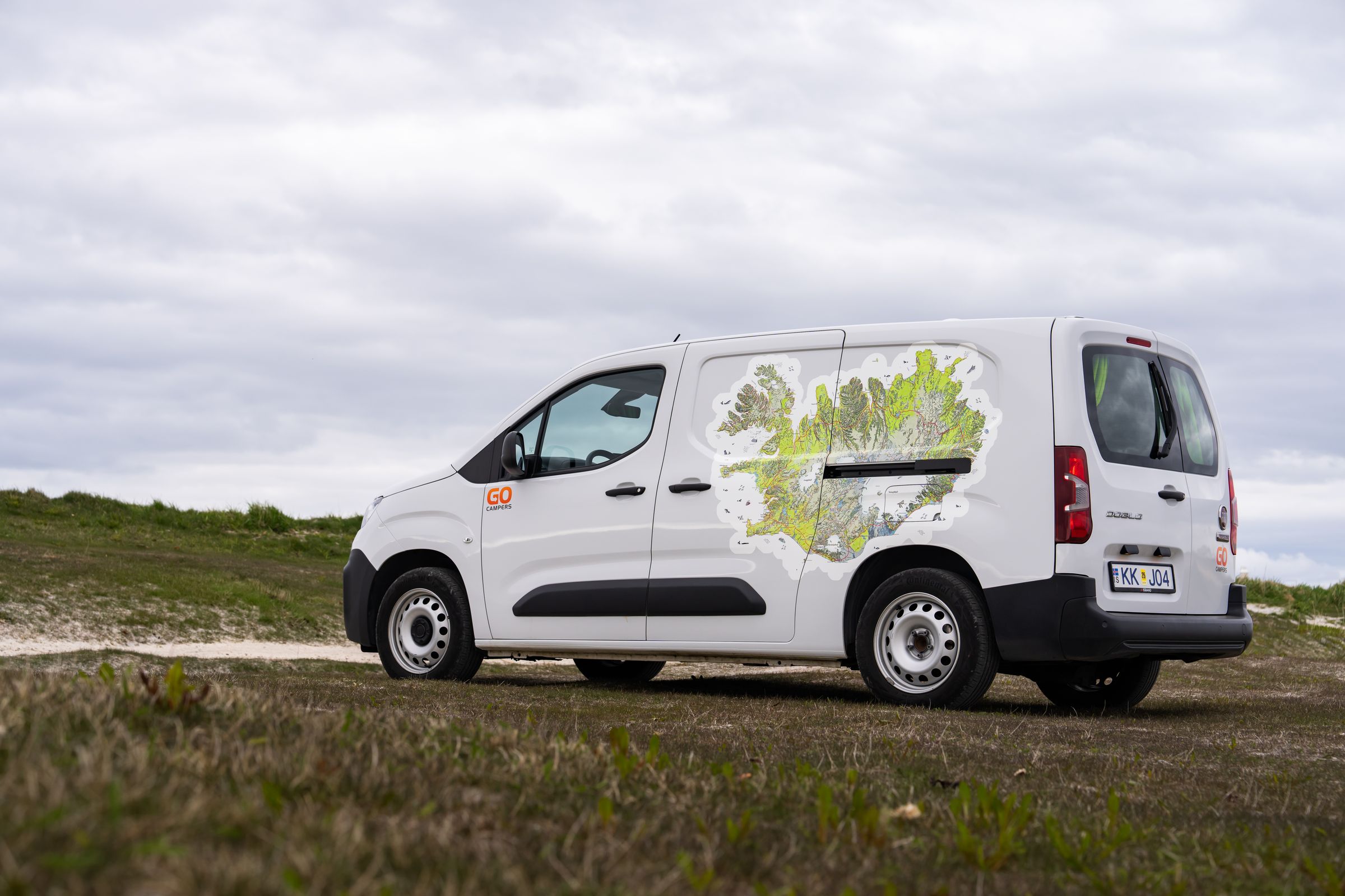 Puertas de la autocaravana compacta cerradas Vista trasera en tres cuartos de una autocaravana compacta para 2 personas, con las puertas cerradas, sobre una pradera en Islandia