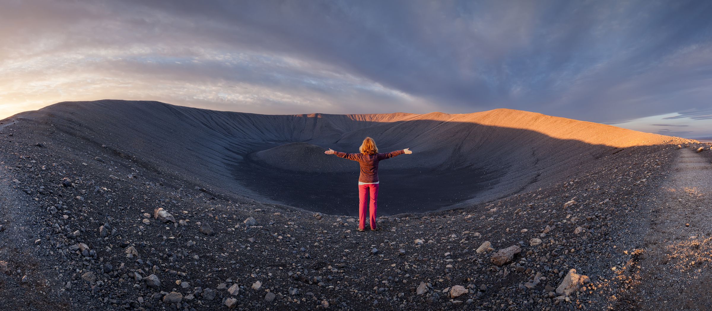 a woman is standing in the middle of a volcano with her arms outstretched at hverfjall east of lake myvatn in iceland.