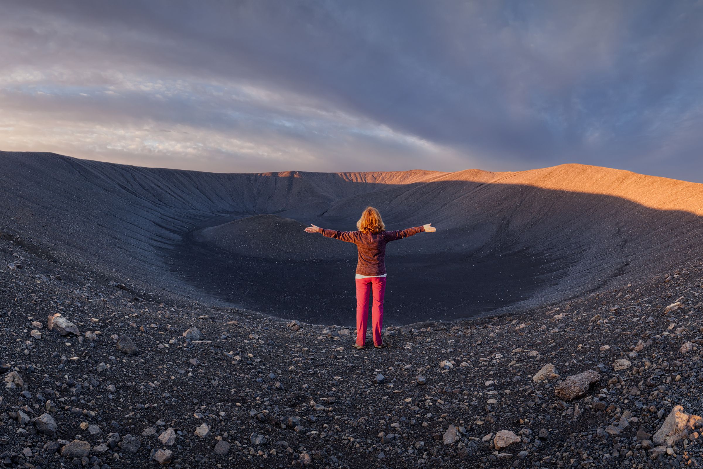 a woman is standing in the middle of a volcano with her arms outstretched at hverfjall east of lake myvatn in iceland.