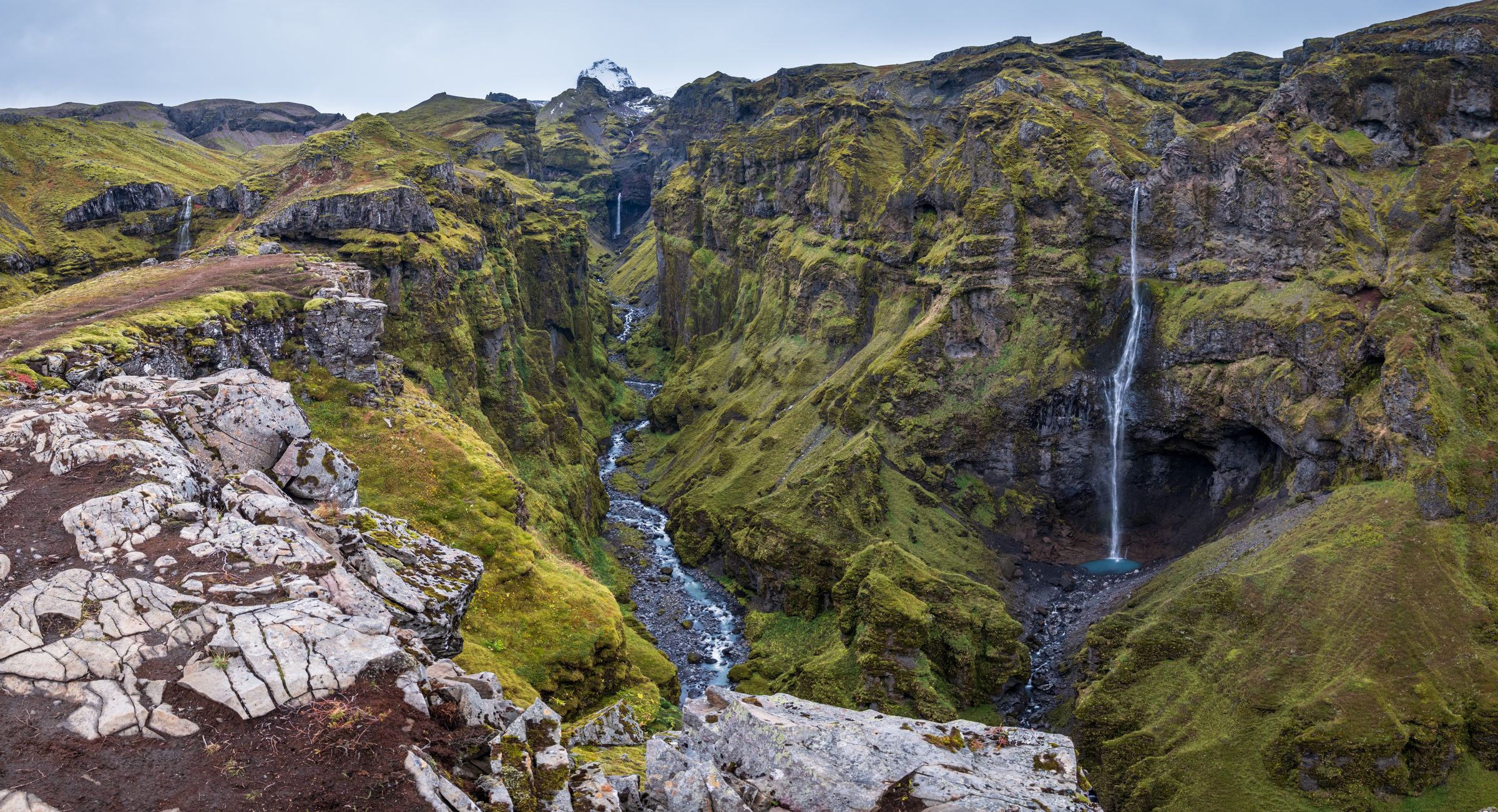 there is a waterfall in the middle of a canyon in the mountains in iceland.