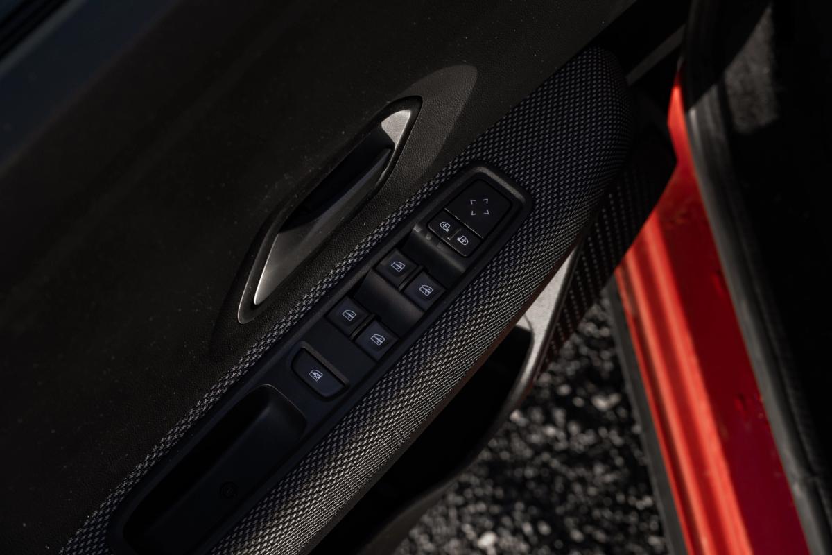 Primer plano del panel de la puerta de un Dacia Jogger, donde se ven los botones de control de las ventanillas y los retrovisores
