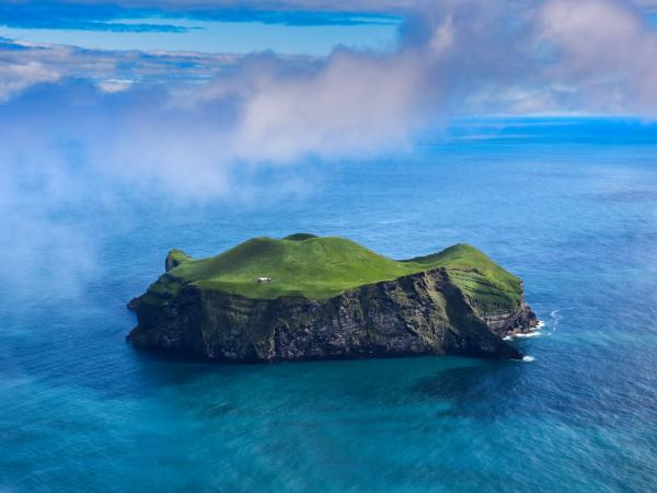 a small green island surrounded by clear blue water