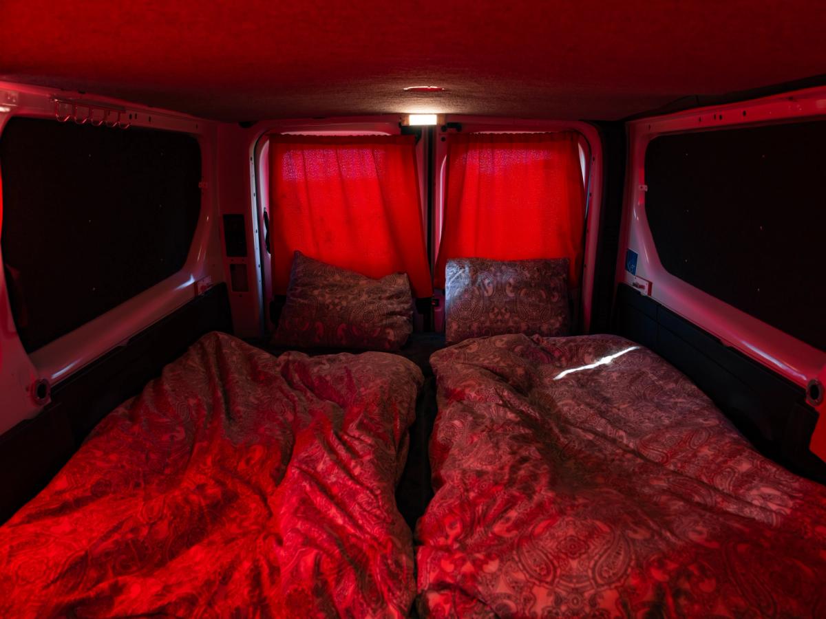 Cortinas traseras cerradas Las cortinas cerradas de las puertas traseras proyectan una luz roja sobre la cama y sus dos almohadas