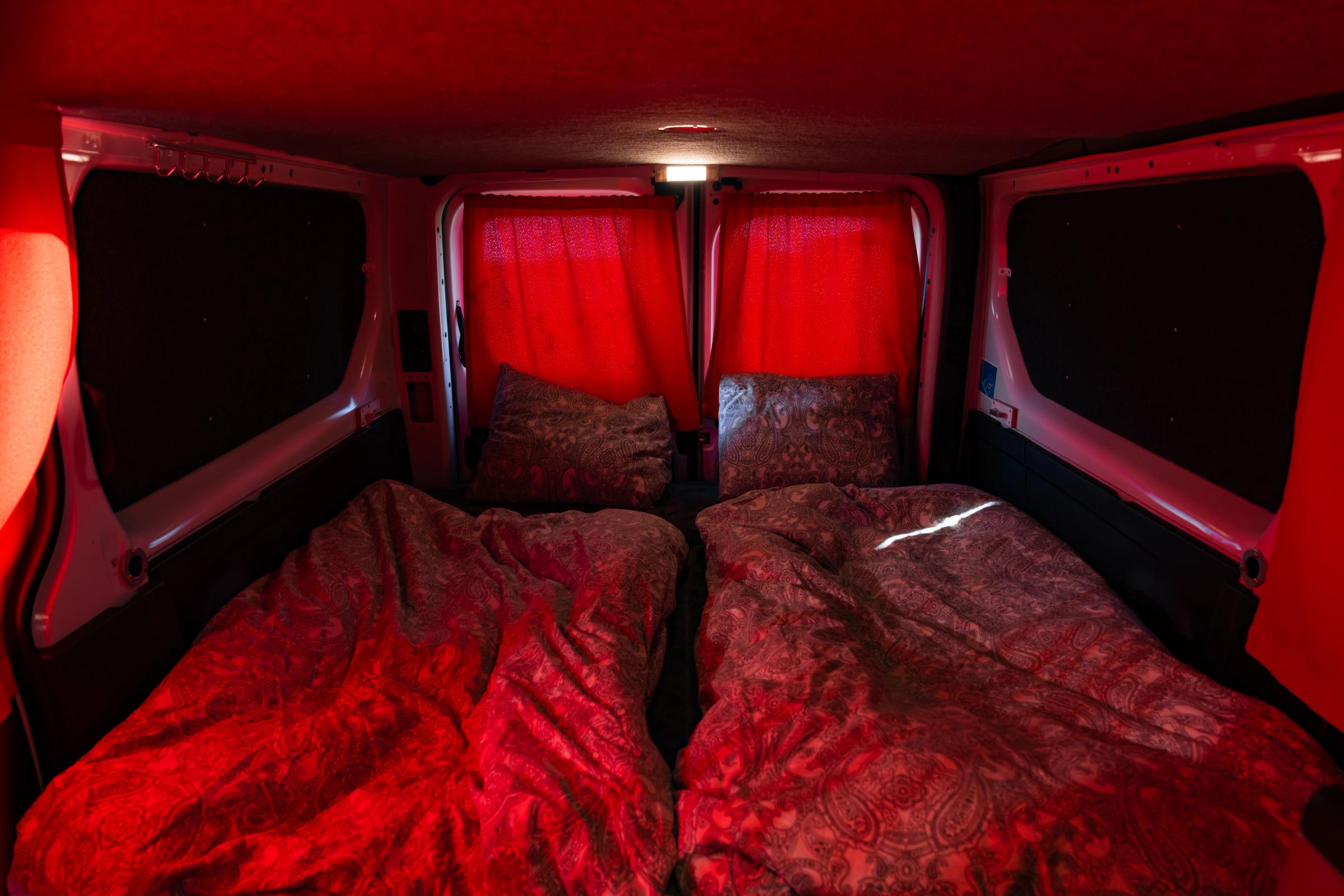Cortinas traseras cerradas Las cortinas cerradas de las puertas traseras proyectan una luz roja sobre la cama y sus dos almohadas