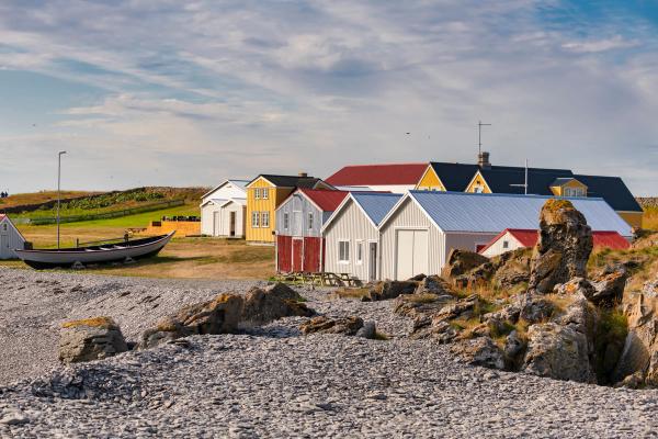 a boat is docked in front of a row of colorful houses on a rocky beach .
