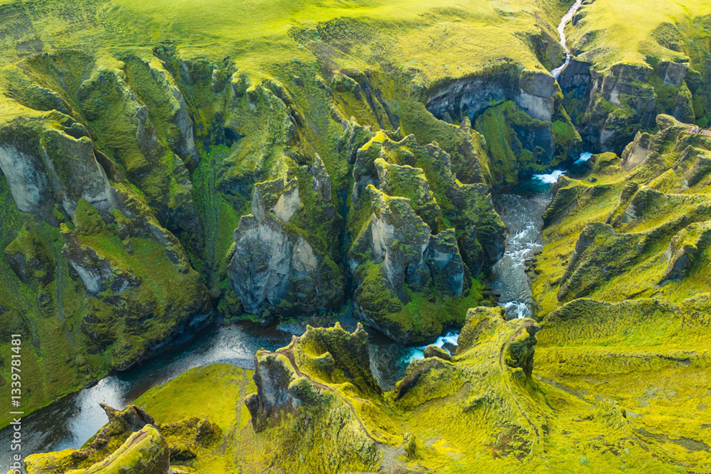 Vista aérea de un río serpenteante a través de un cañón profundo y cubierto de musgo verde.