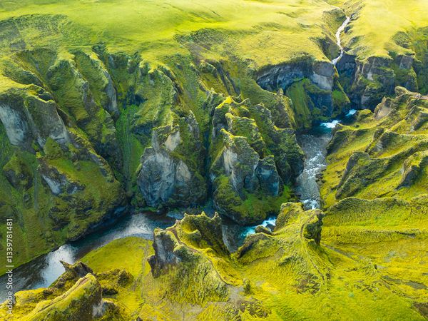 Aerial view of a mossy green canyon with a winding river.