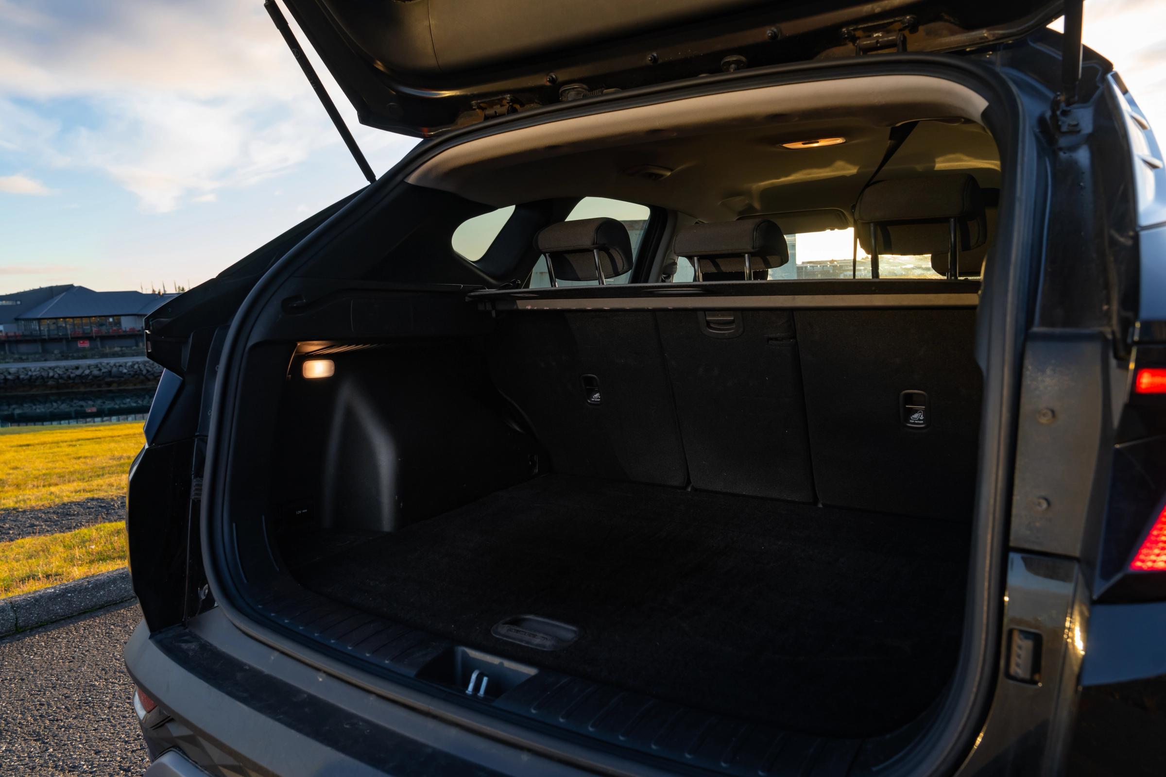 Hyundai Tucson avec hayon ouvert, montrant un coffre vide et moquetté ainsi que des dossiers de sièges arrière rabattables séparément