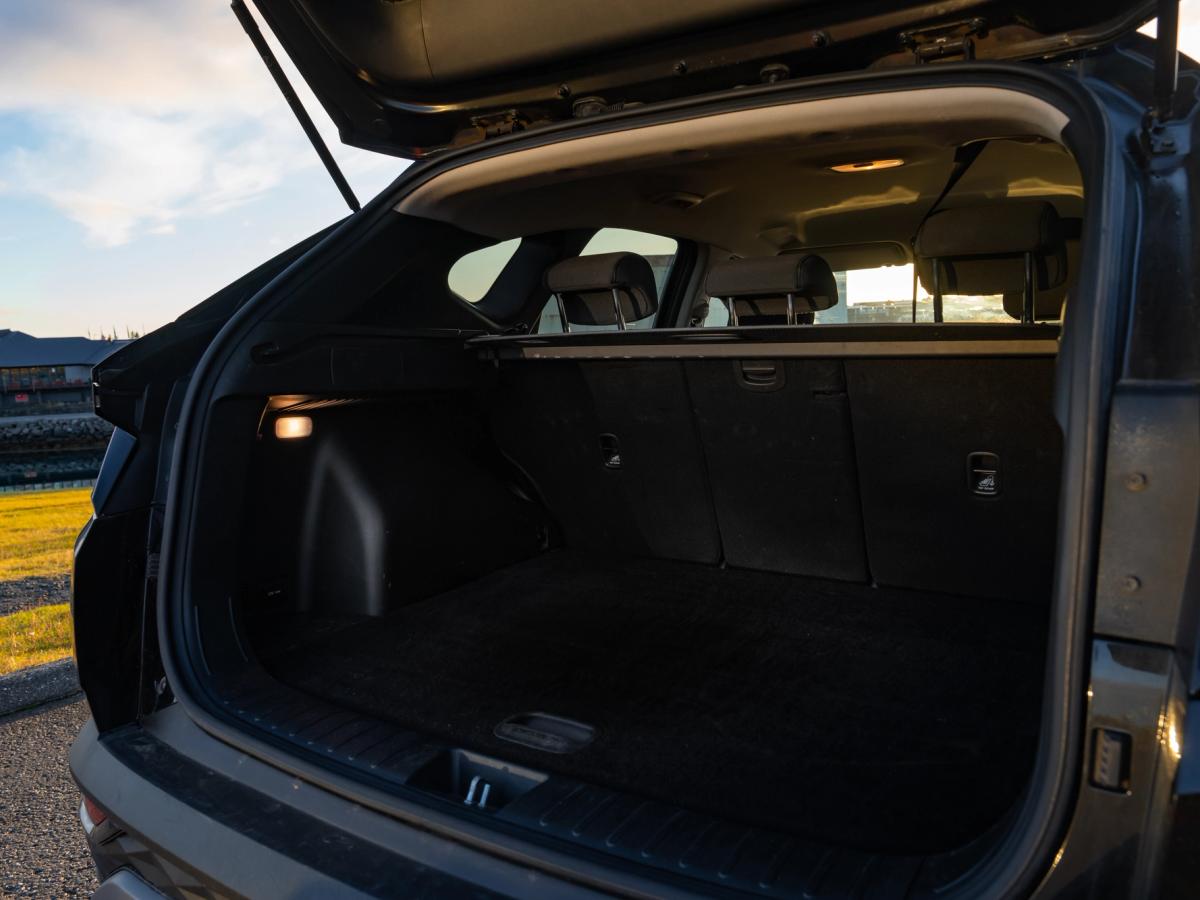 Espace du coffre ouvert du Tucson Hyundai Tucson avec hayon ouvert, montrant un coffre vide et moquetté ainsi que des dossiers de sièges arrière rabattables séparément