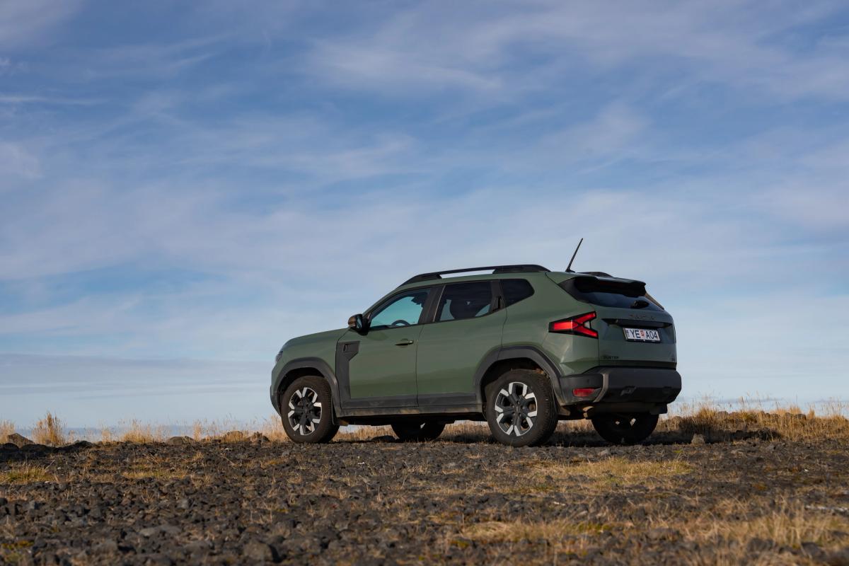 Grande plano do volante de um Dacia Duster, com o painel de instrumentos e uma vista para o rio no exterior