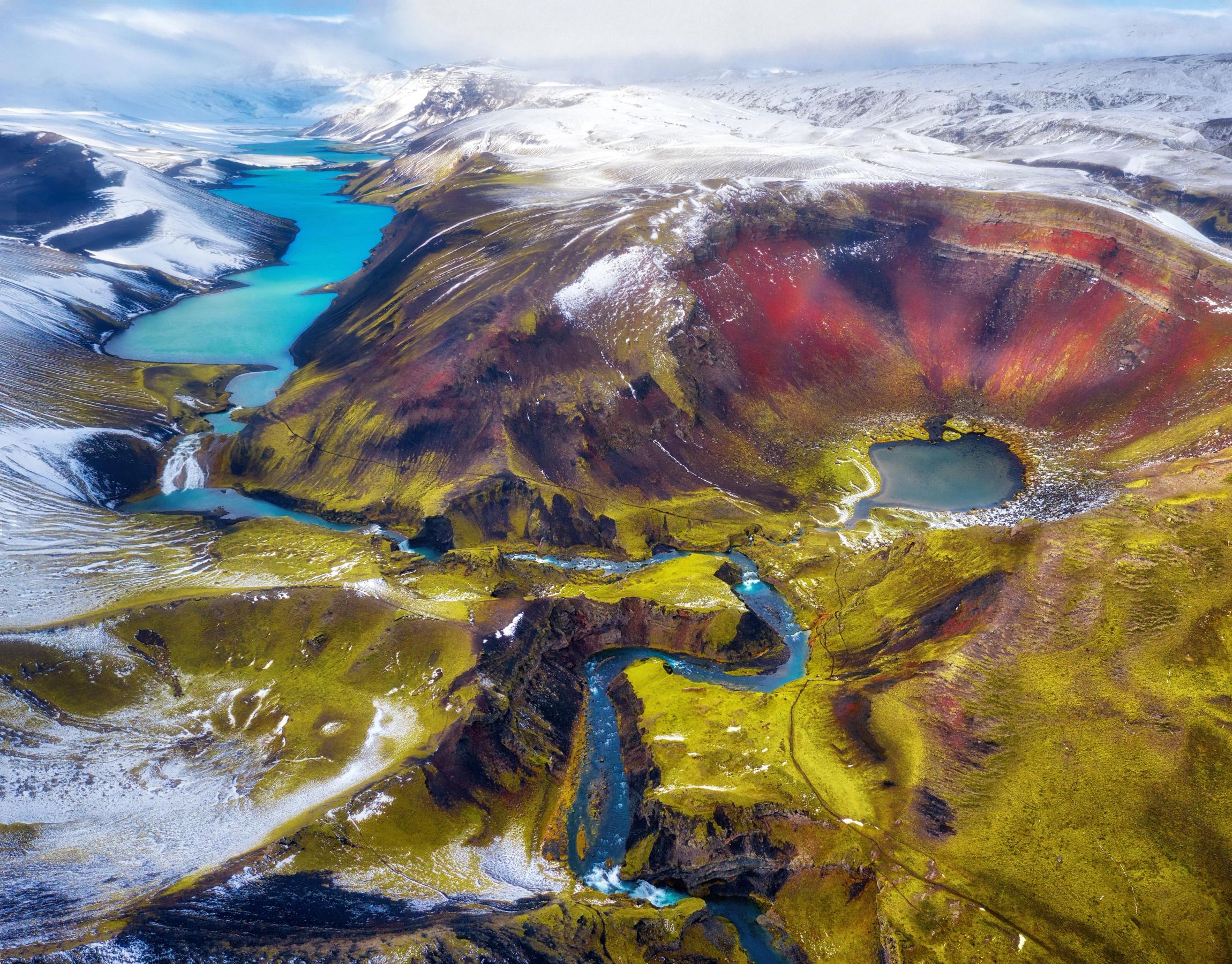 an aerial view of a colorful mountain landscape with a river running through it .