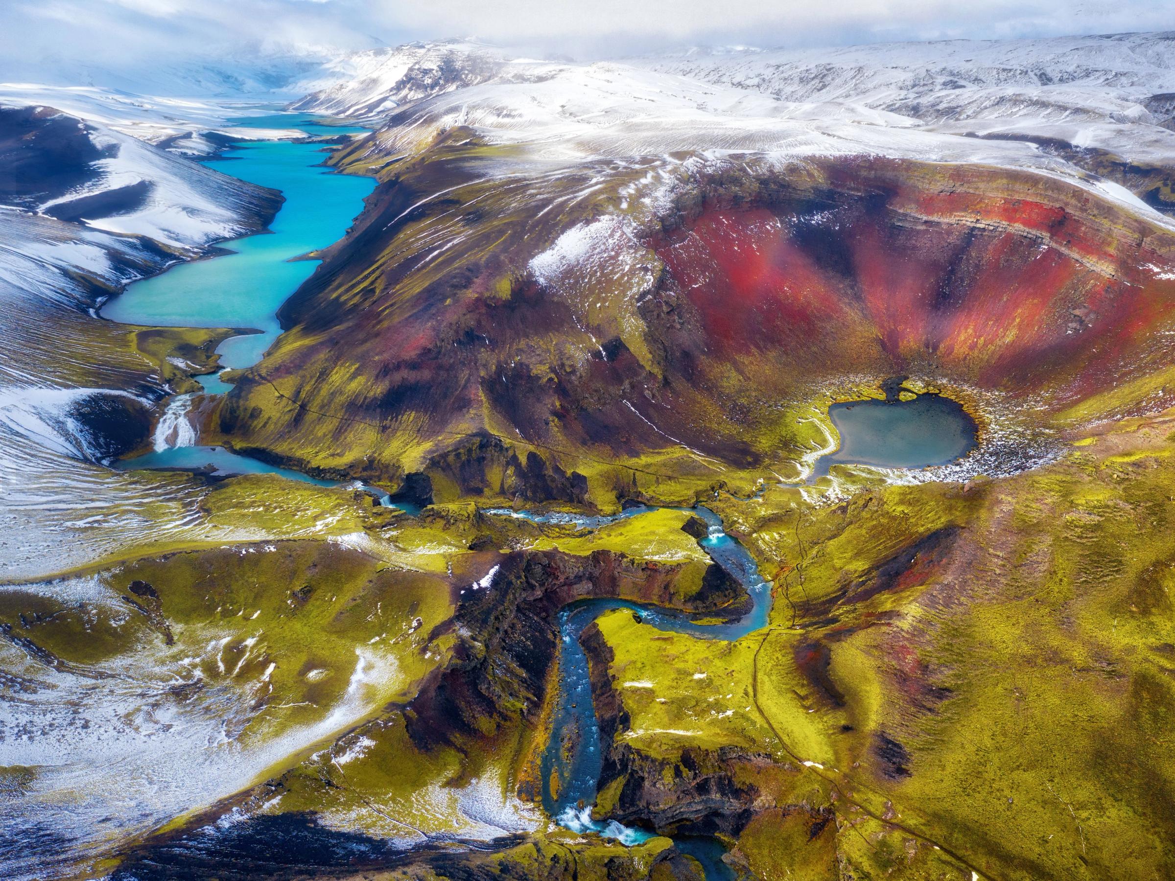 an aerial view of a colorful mountain landscape with a river running through it .