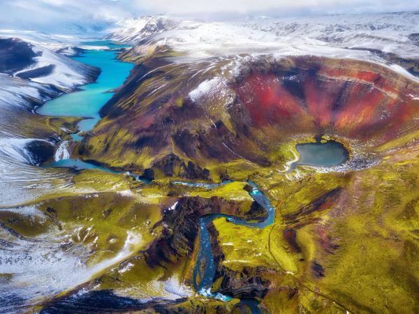 an aerial view of a colorful mountain landscape with a river running through it .