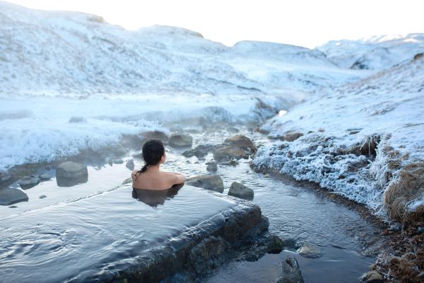hot spring Woman in a hot spring in Iceland watching the sun rises during a chilly weather