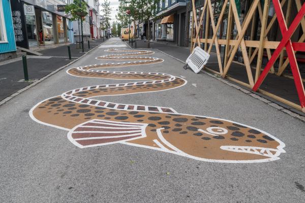 el asfalto de una calle pintado con el dibujo de un gran pez marrón, blanco y negro