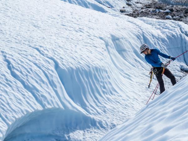 una persona está escalando una montaña nevada con una cuerda.
