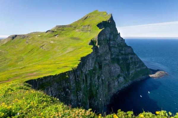 a cliff overlooking the ocean with a mountain in the background .