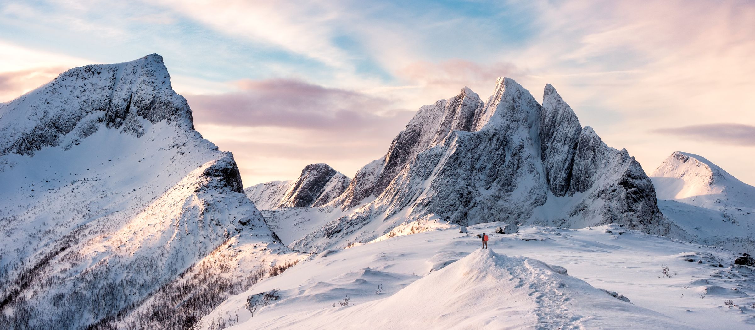 two people are standing on top of a snow covered mountain .