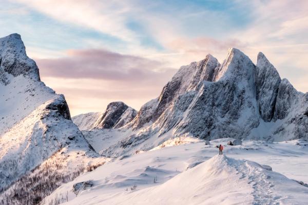 two people are standing on top of a snow covered mountain .