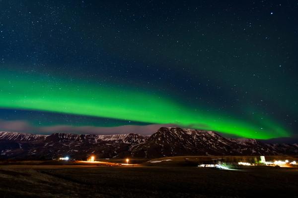Northern lights in the countryside, Iceland Northern lights with blue and starry sky in the countryside, snowy mountains in the background