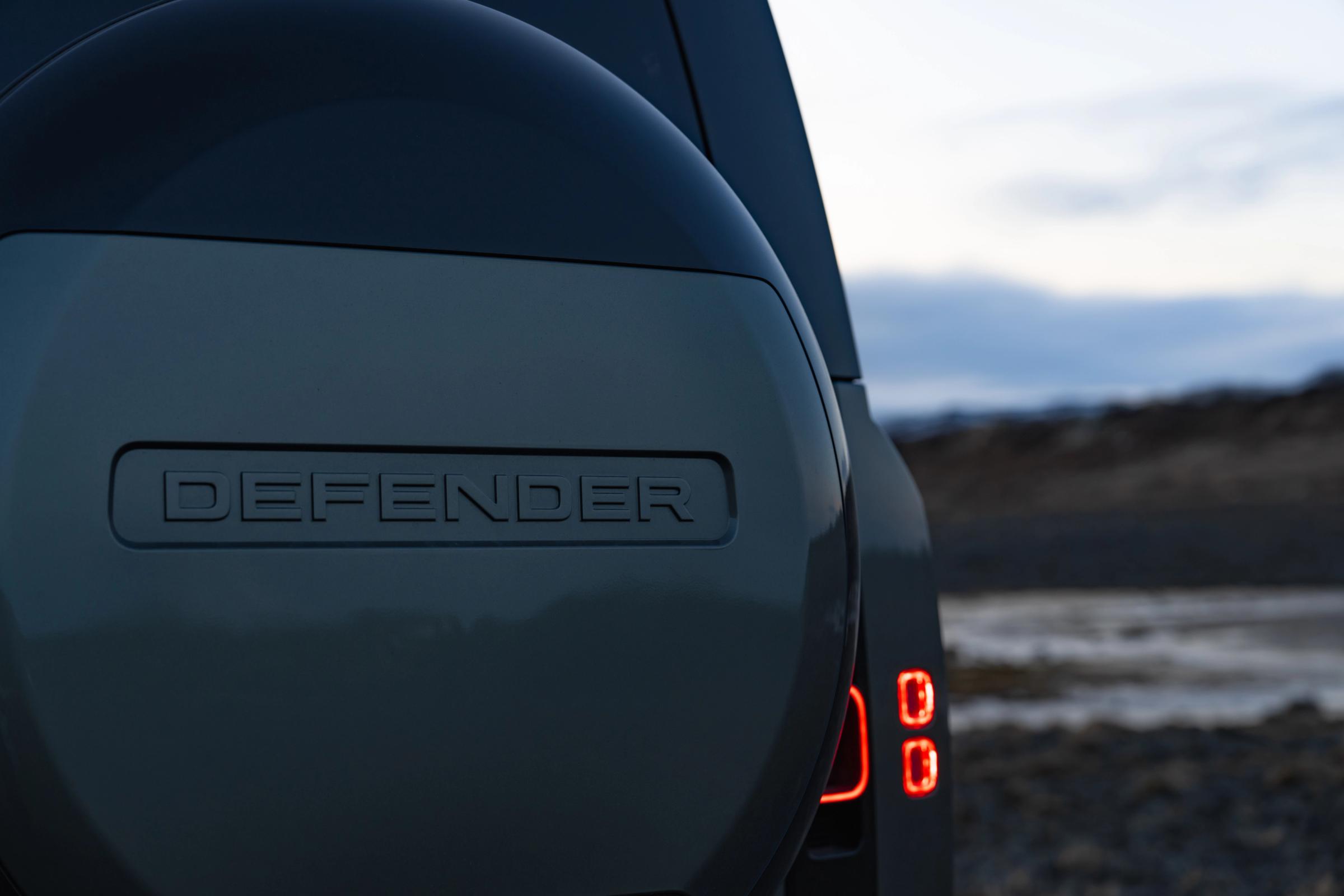 Primer plano de la rueda de repuesto trasera y el piloto trasero de un Land Rover Defender de alquiler en Islandia, disponible en Go Car Rental