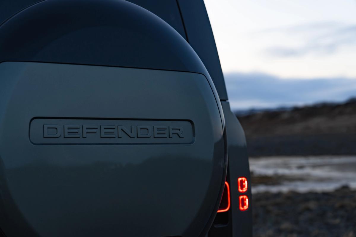 Primer plano de la rueda de repuesto trasera y el piloto trasero de un Land Rover Defender de alquiler en Islandia, disponible en Go Car Rental