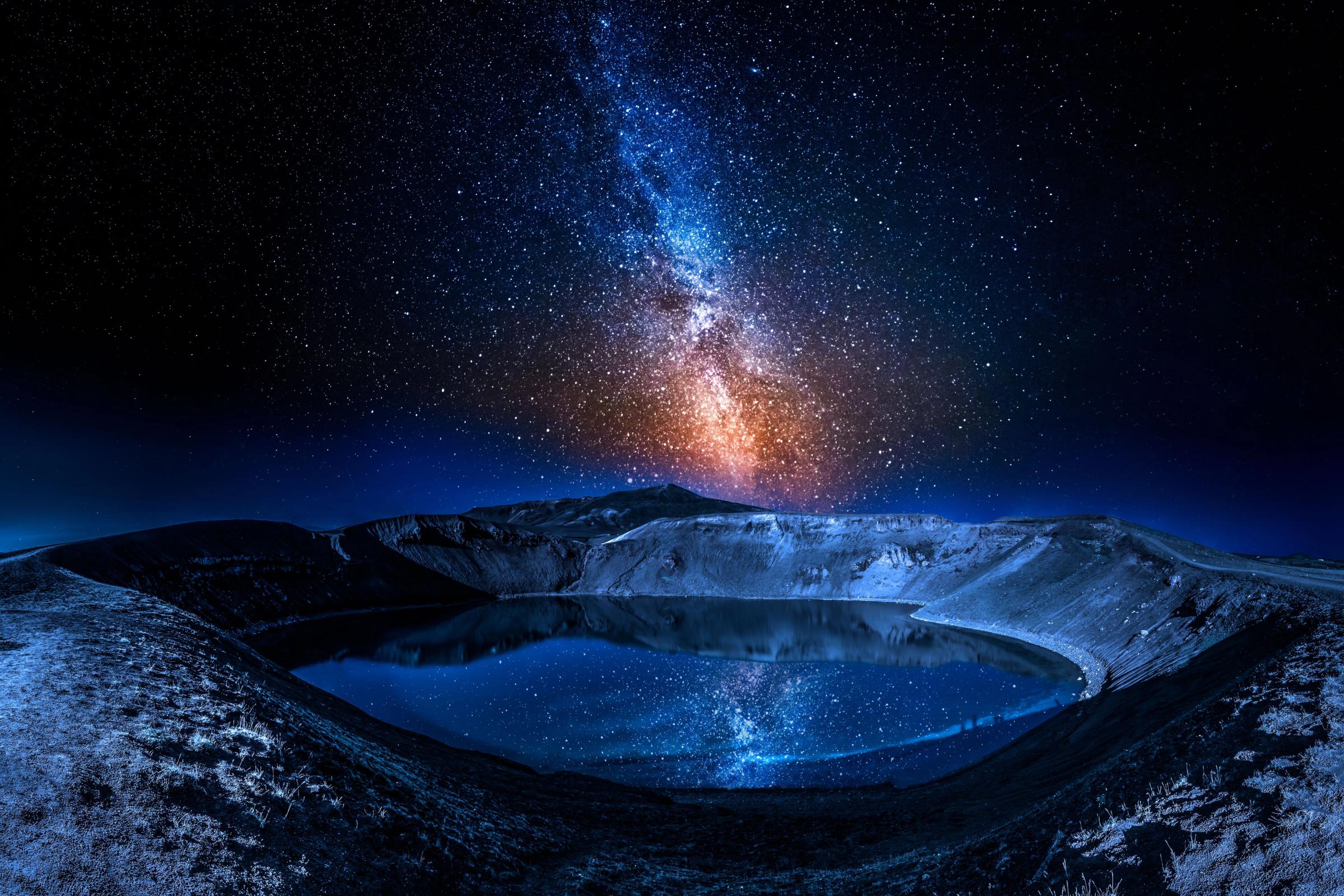 the milky way is visible over a lake in the middle of a mountain .