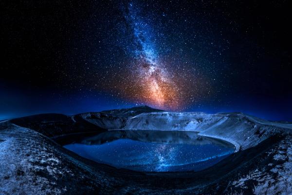 the milky way is visible over a lake in the middle of a mountain .