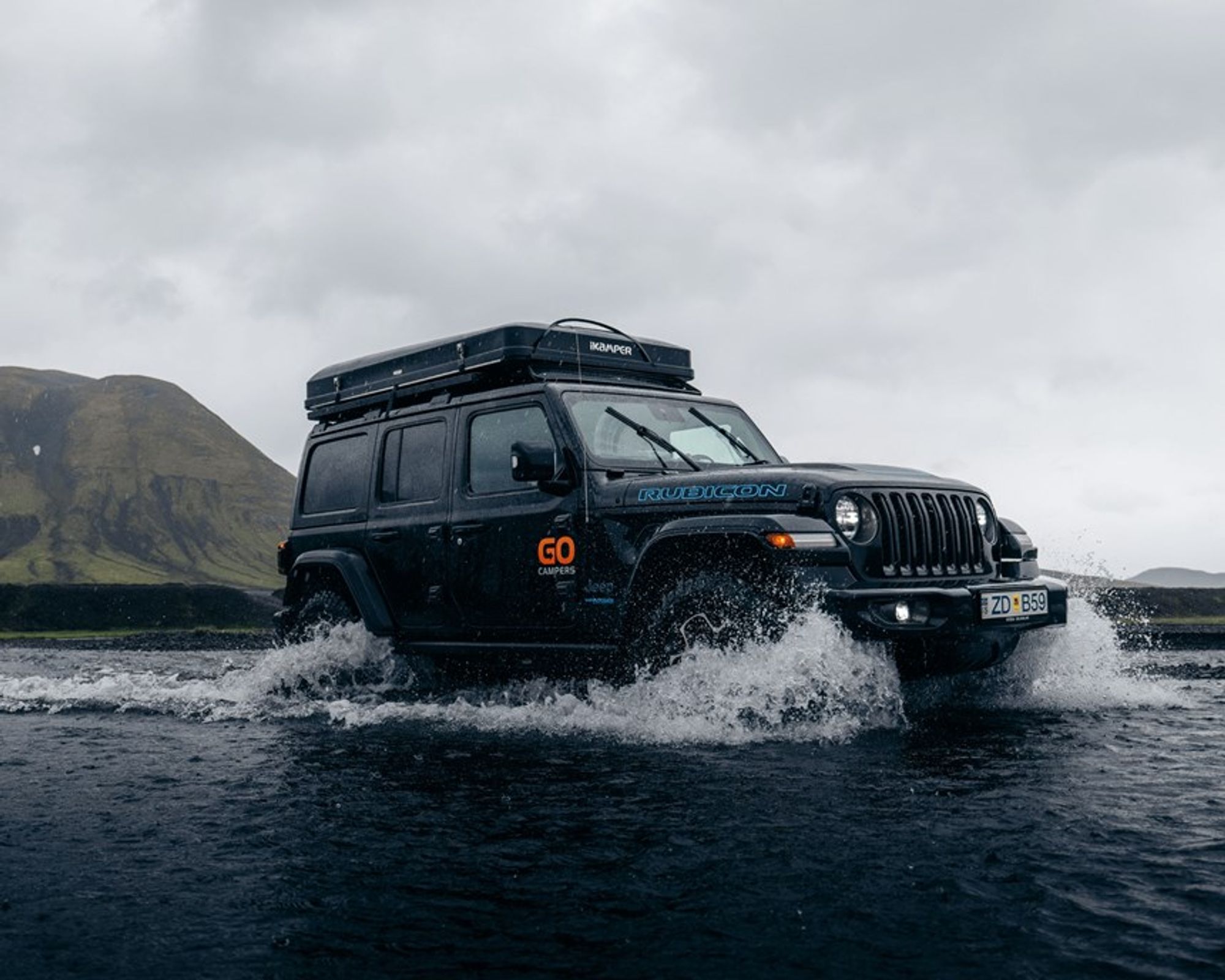 a jeep with a tent on top of it is driving through a river at the highlands in iceland.