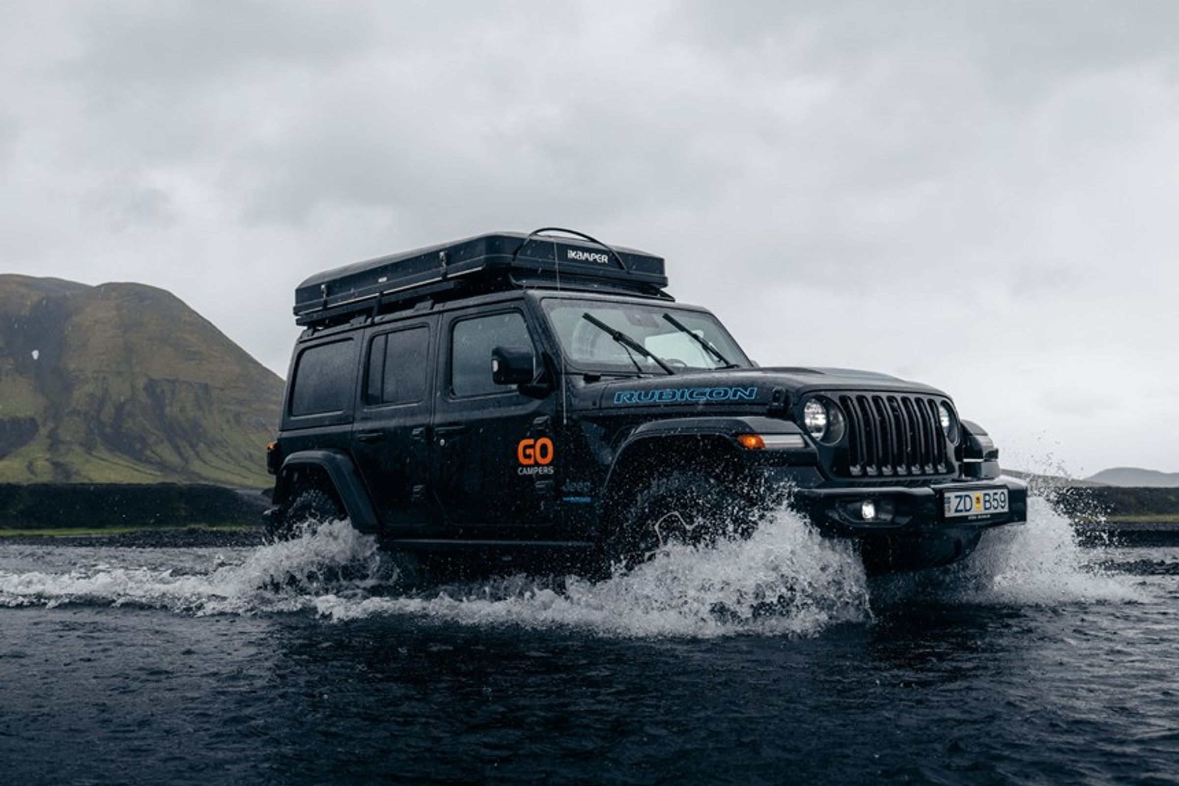 a jeep with a tent on top of it is driving through a river at the highlands in iceland.