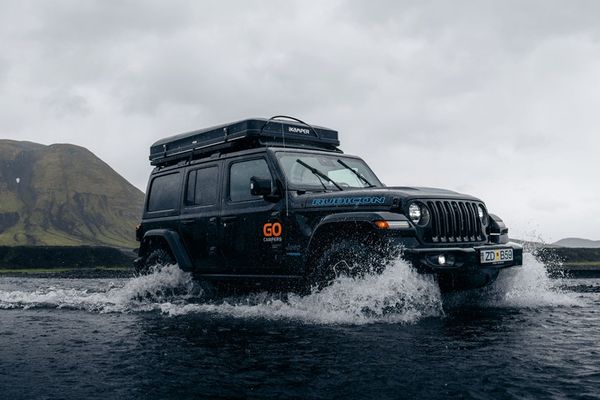 a jeep with a tent on top of it is driving through a river at the highlands in iceland.