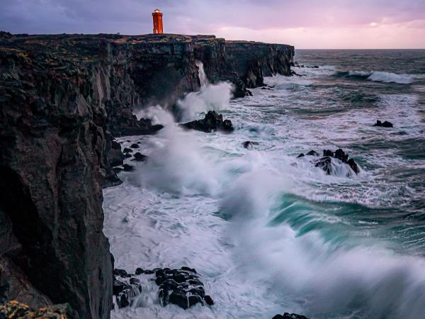 a lighthouse on top of a rocky cliff overlooking the ocean .