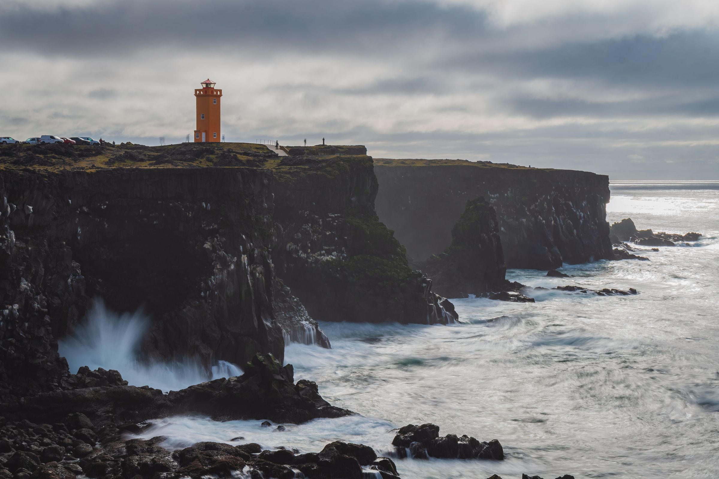 un faro de color naranja sobre un acantilado en un día nublado