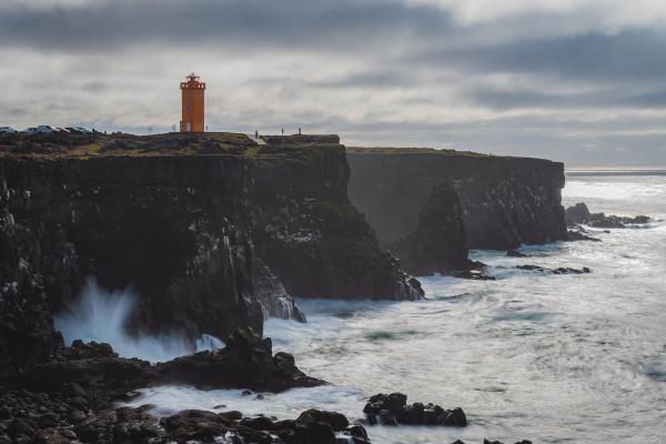 un faro de color naranja sobre un acantilado en un día nublado