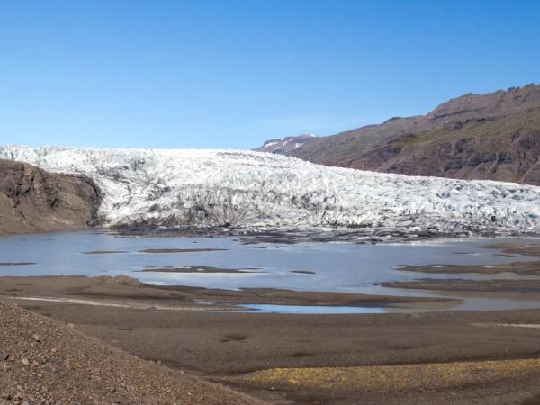 two people admiring a big glacier on a sunny day