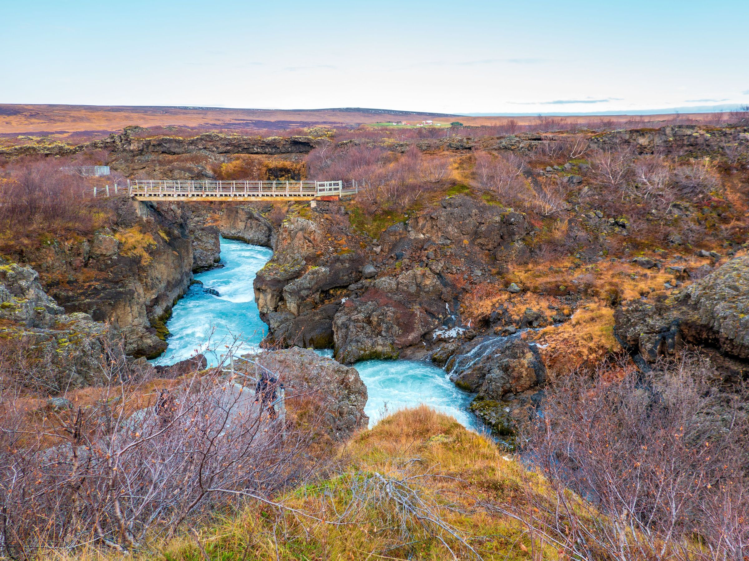 there is a bridge over a river in the middle of a canyon .