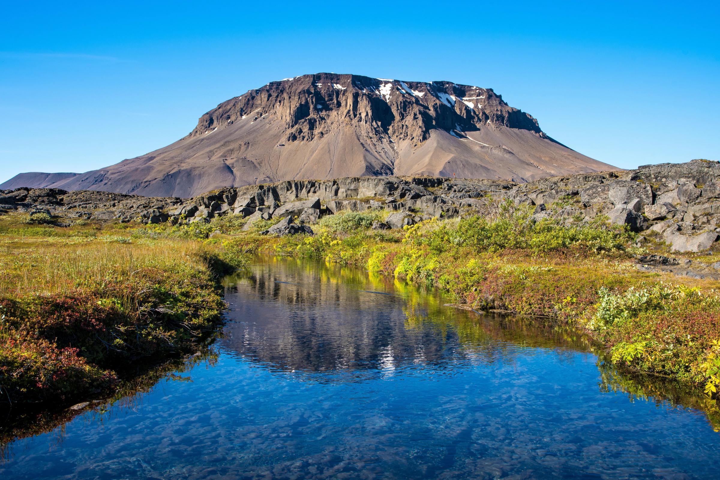 there is a mountain in the background and a river in the foreground .